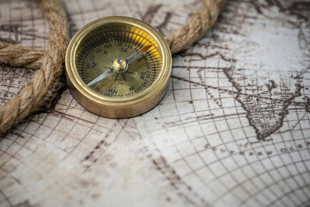 A vintage brass compass rests on an antique map with a nautical rope, evoking exploration and discovery.