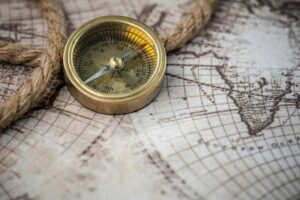 A vintage brass compass rests on an antique map with a nautical rope, evoking exploration and discovery.