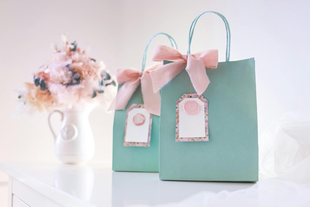 Two pastel gift bags with pink bows and blank tags, perfect for celebrations or parties.