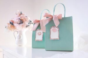 Two pastel gift bags with pink bows and blank tags, perfect for celebrations or parties.