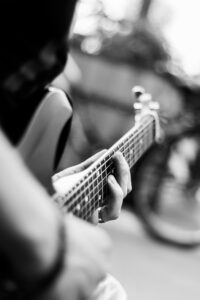 Close-up of a guitarist's hands on the fretboard in black and white.
