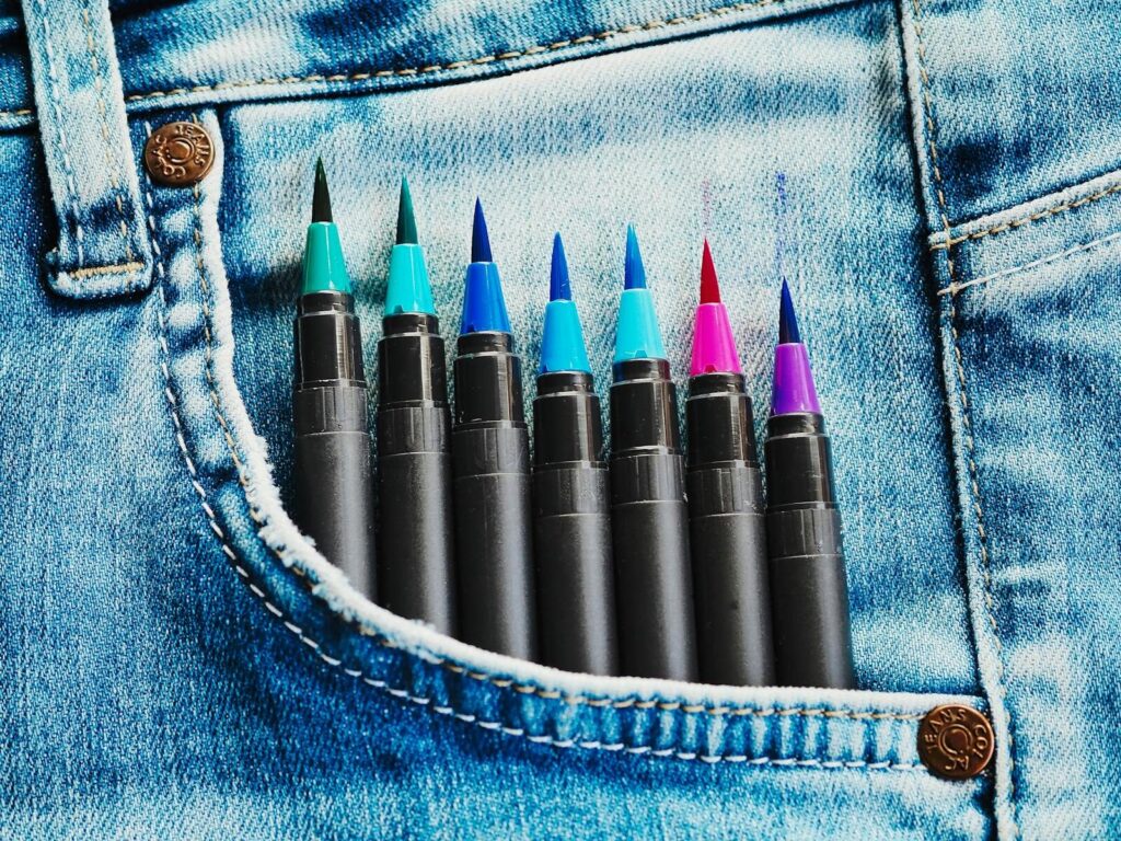Vibrant markers creatively arranged in a jeans pocket showcasing artistry and design.