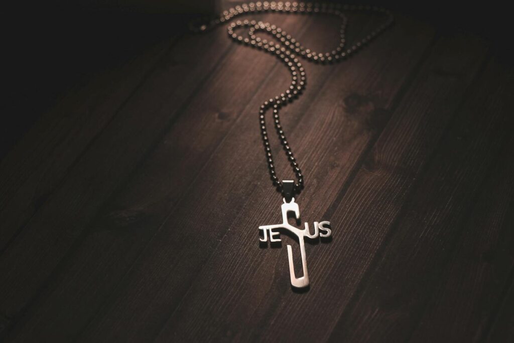 Close-up of a silver Jesus cross necklace on a dark wooden background, evoking spirituality and faith.