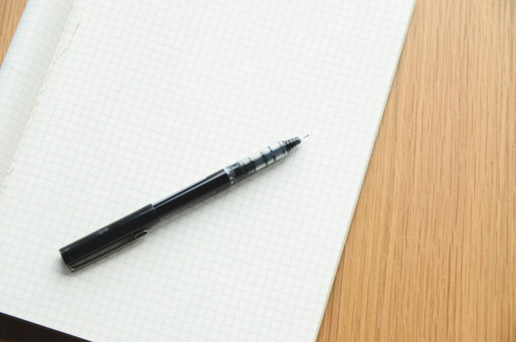 Black pen resting on an open grid notebook, perfect for writing or design.
