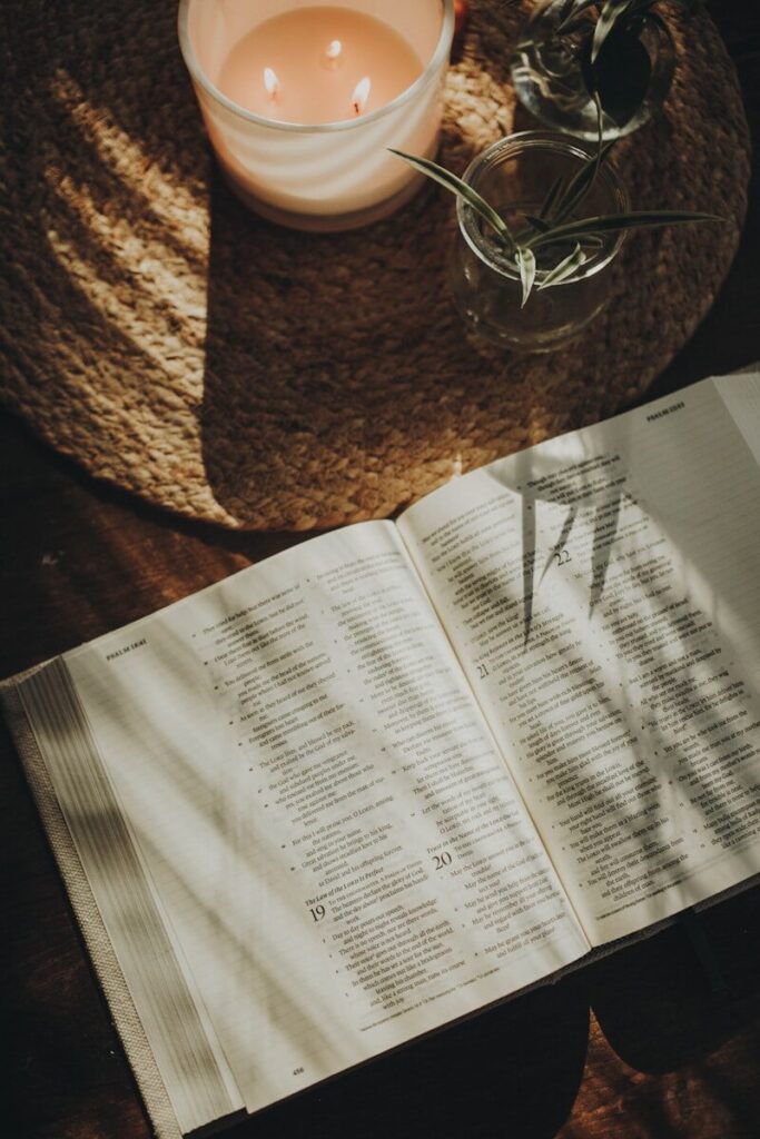 an open book sitting on top of a table next to a candle