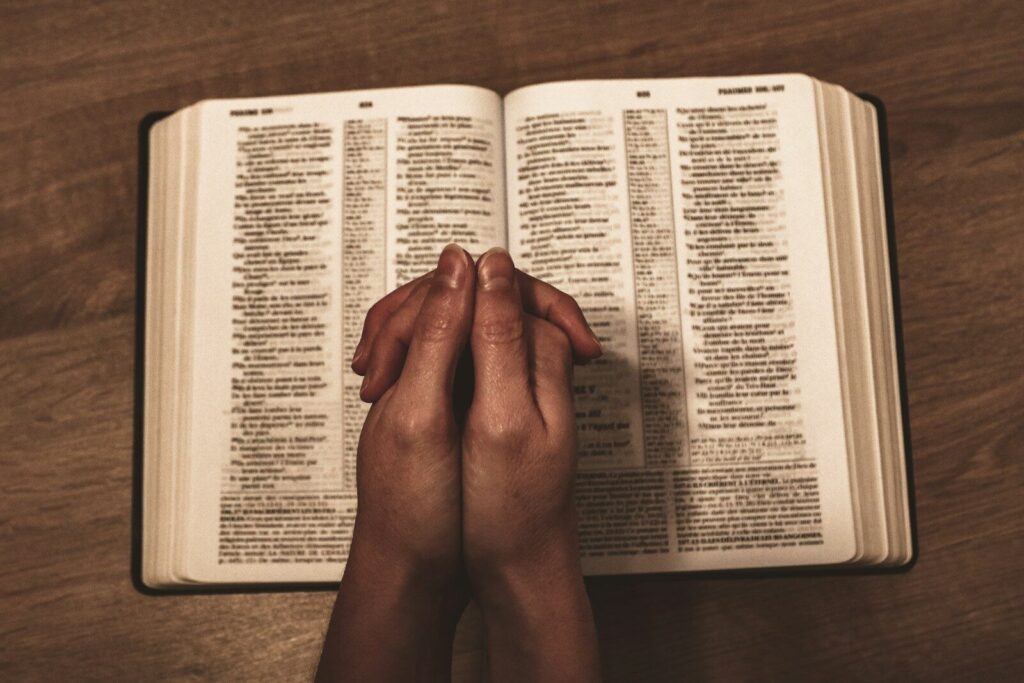 praying hands resting on a bible