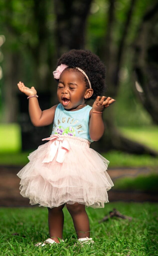 Adorable toddler with afro hair wearing a tutu, playing outside in Aburi, Ghana.