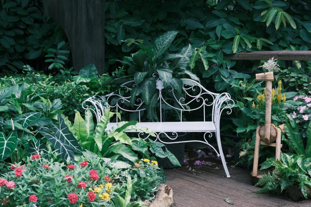 Exquisite white metal bench surrounded by vibrant garden foliage and colorful flowers.