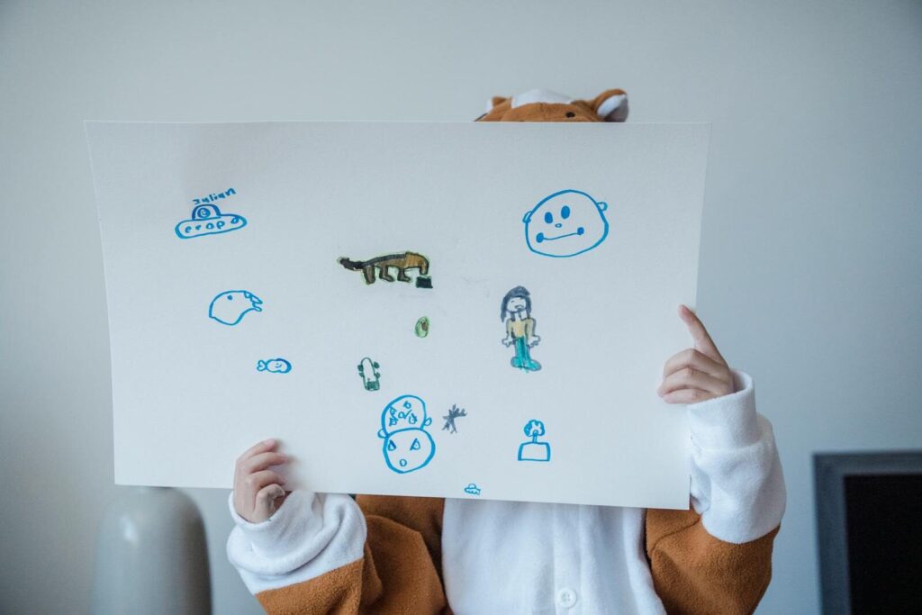 A child in a costume holds a playful drawing with colorful sketches, expressing creativity.