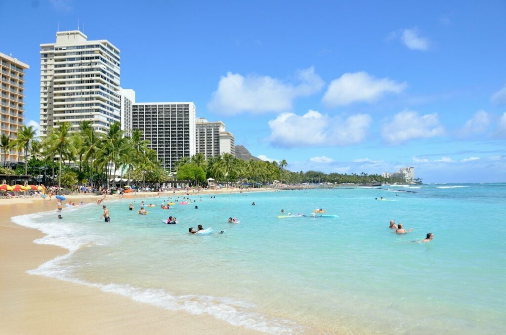 a beach with people swimming in the water at Waikiki