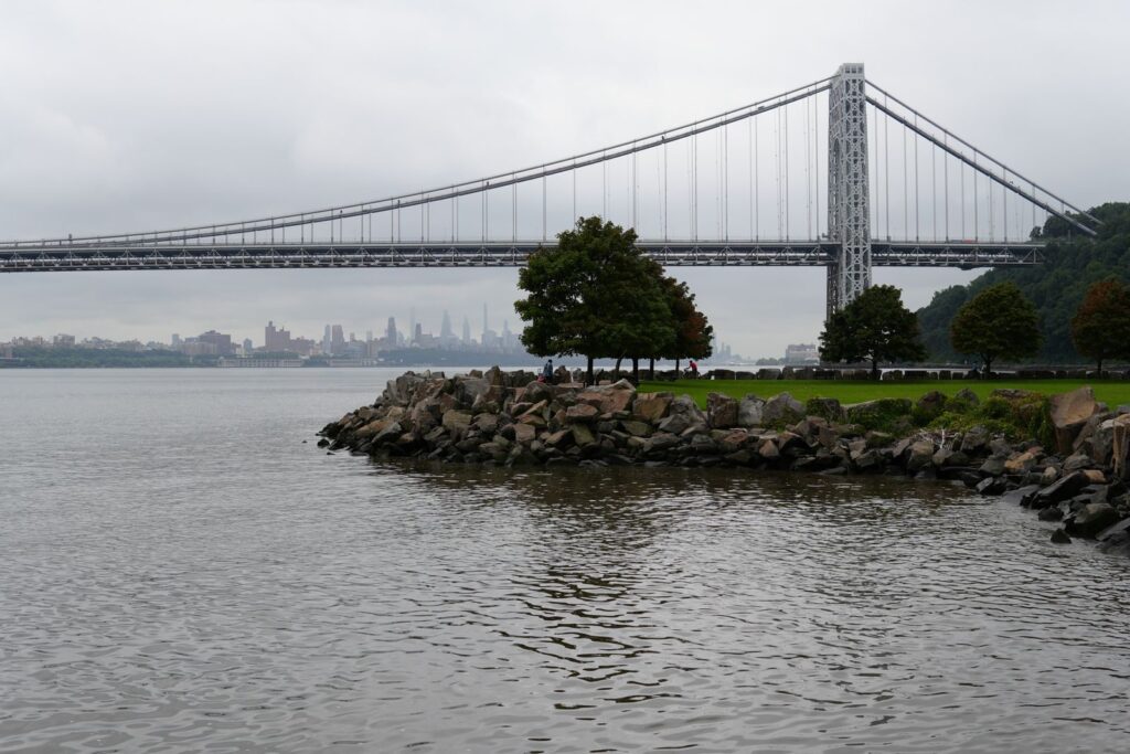 View of the George Washington Bridge spanning the Hudson River with New York City skyline in the background.