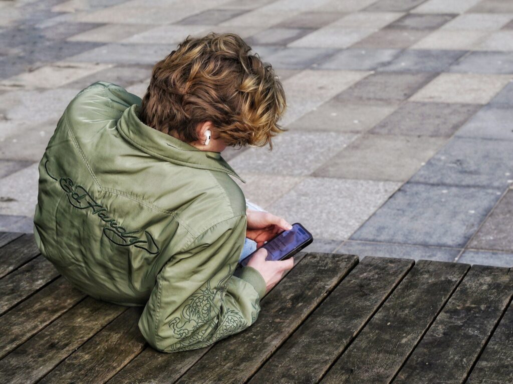 Safe Christian Apps for Teens; Young person with curly hair using a smartphone.