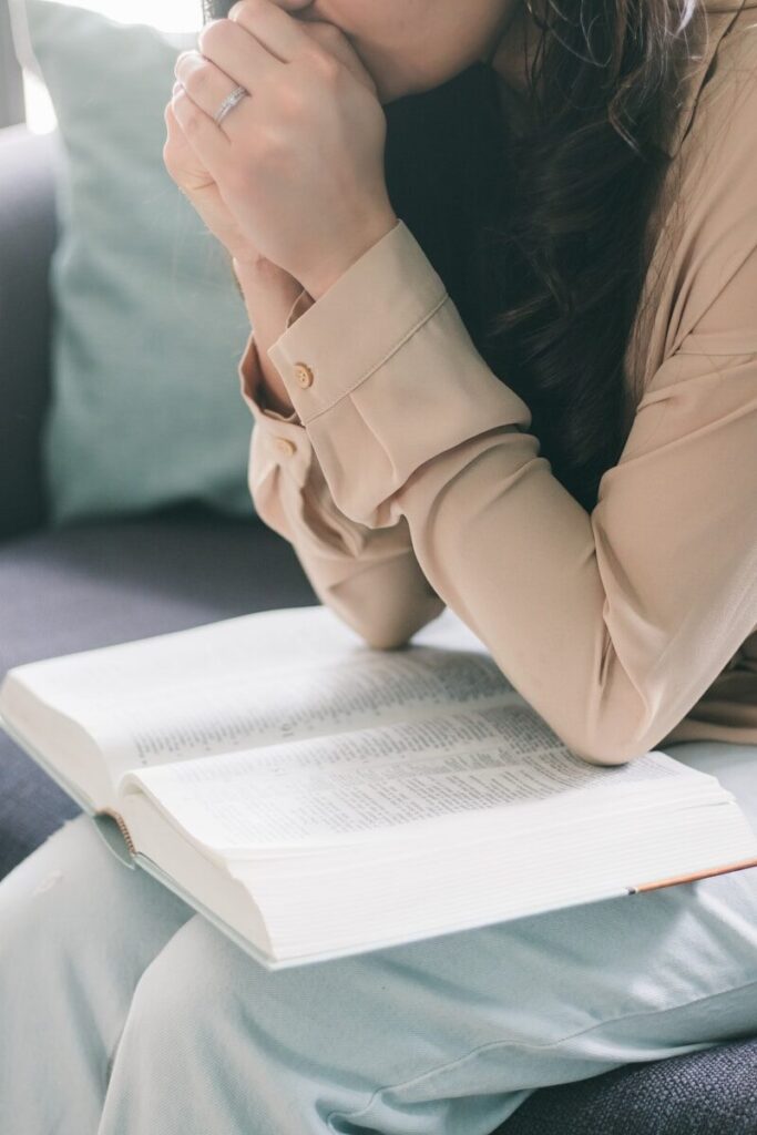 woman in beige blazer sitting on white bed; Creative Ways to Memorize Bible Verses