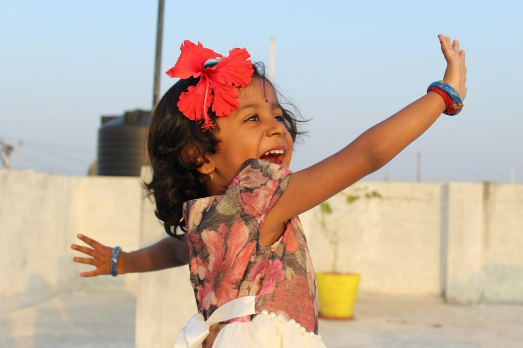music and movement; a little girl that is standing up with her arms in the air